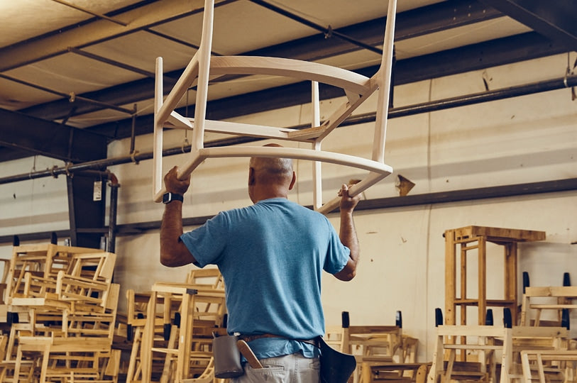 Photo of a person carrying a chair frame.