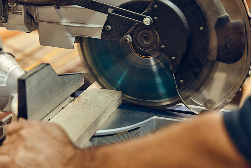 Close-up photo of a person using a miter saw.